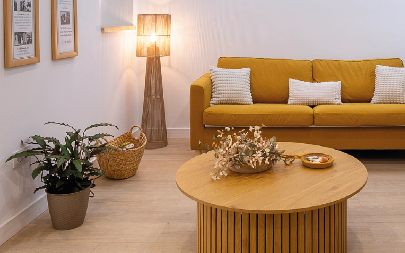 Sala cálida con sofá mostaza, lámpara de pie y decoración natural
