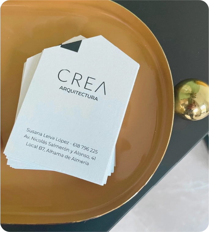 Tarjeta de visita de CREA Arquitectura sobre bandeja dorada
